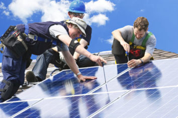 group of men installing solar panels to a roof