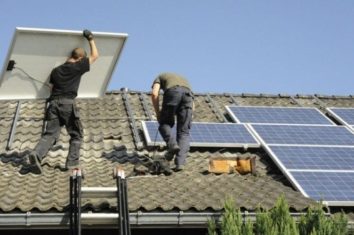 men installing solar panels on a roof