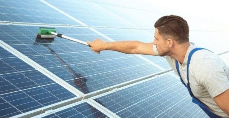 man cleaning his solar panels with a squeegee