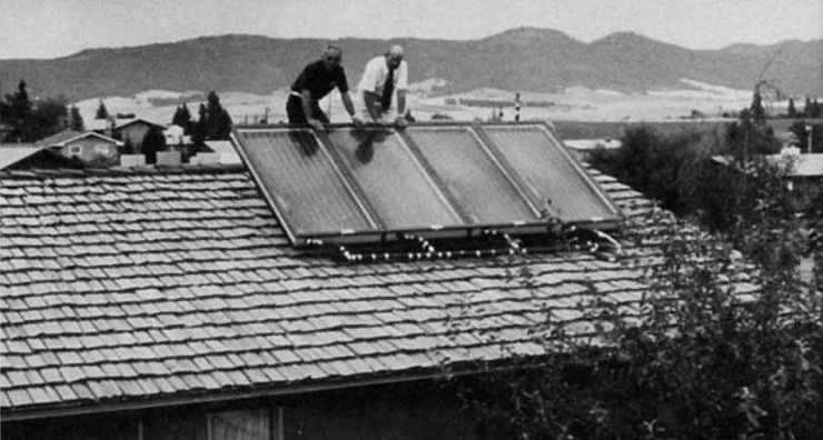 old photograph of two men fixing a solar panel system to a roof