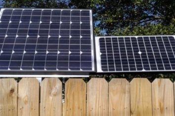 two different sizes of solar panels side by side behind a fence
