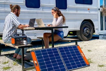 a couple using a solar generator to connect their laptops
