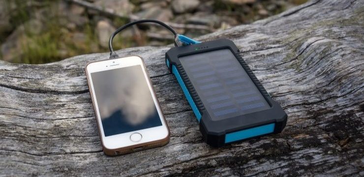 Portable solar panel for charging mobile devices lying on a log in the woods