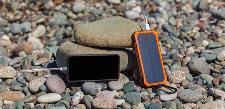a solar power bank connected to a cell phone on the stones