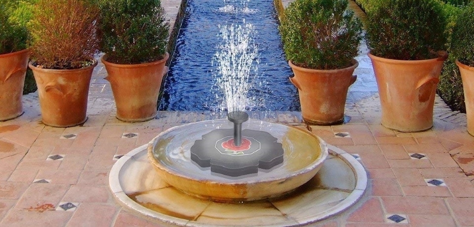 a solar powered water pump near some flower pots