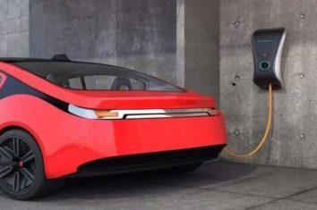 An electric vehicle charging station connected to a red car