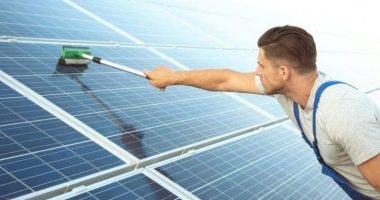 man cleaning his solar panels with a squeegee