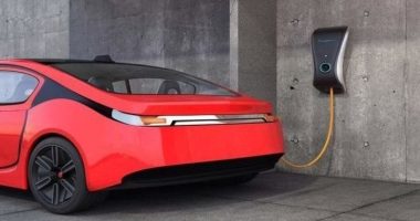 An electric vehicle charging station connected to a red car