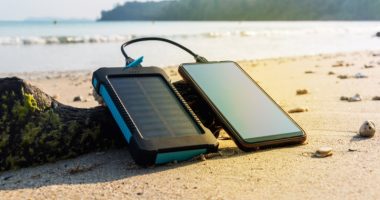image showing a solar battery charger connected to a mobile phone on the beach