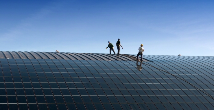 people installing solar panels on the roof of a company